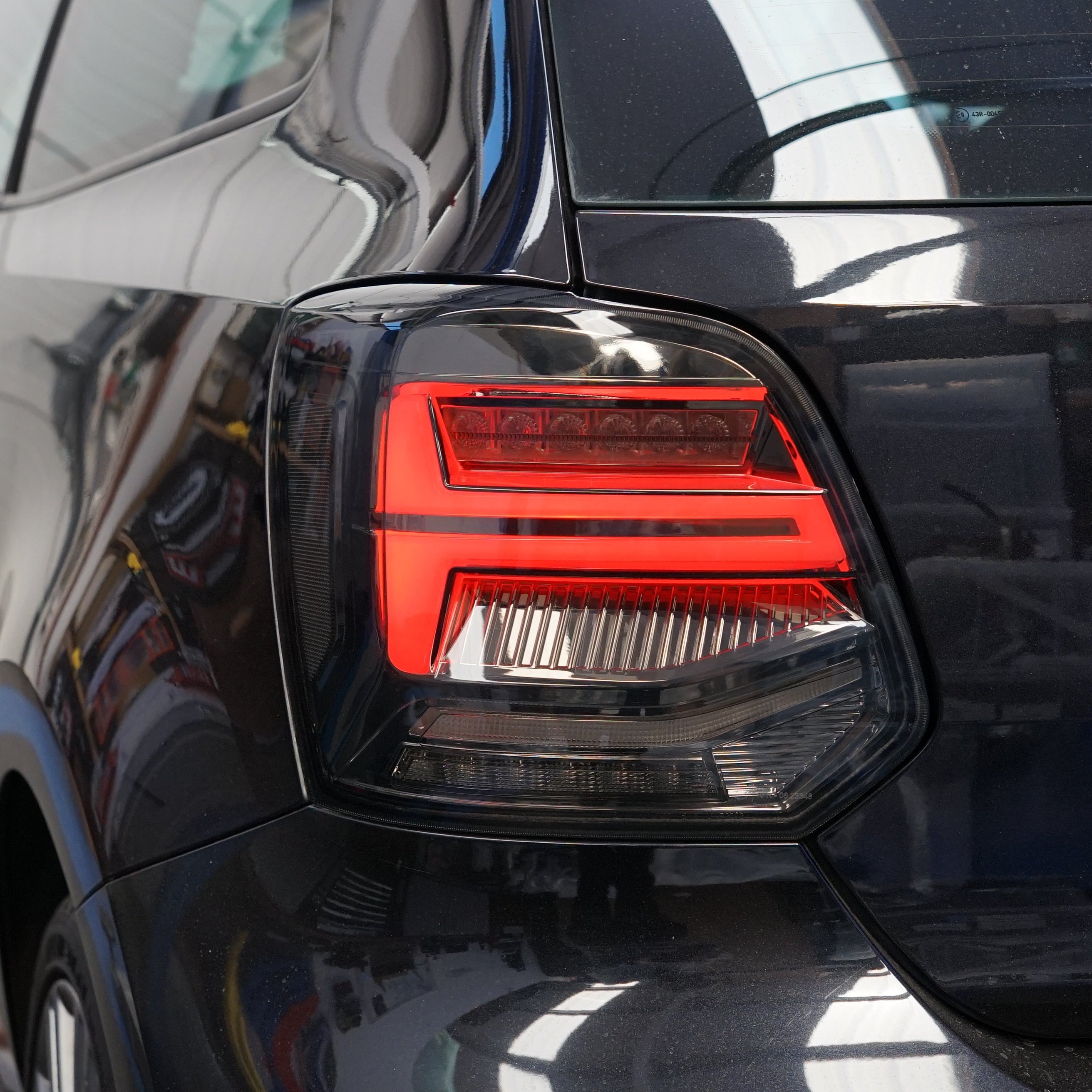 Close-up of a car's red taillight on a black vehicle.