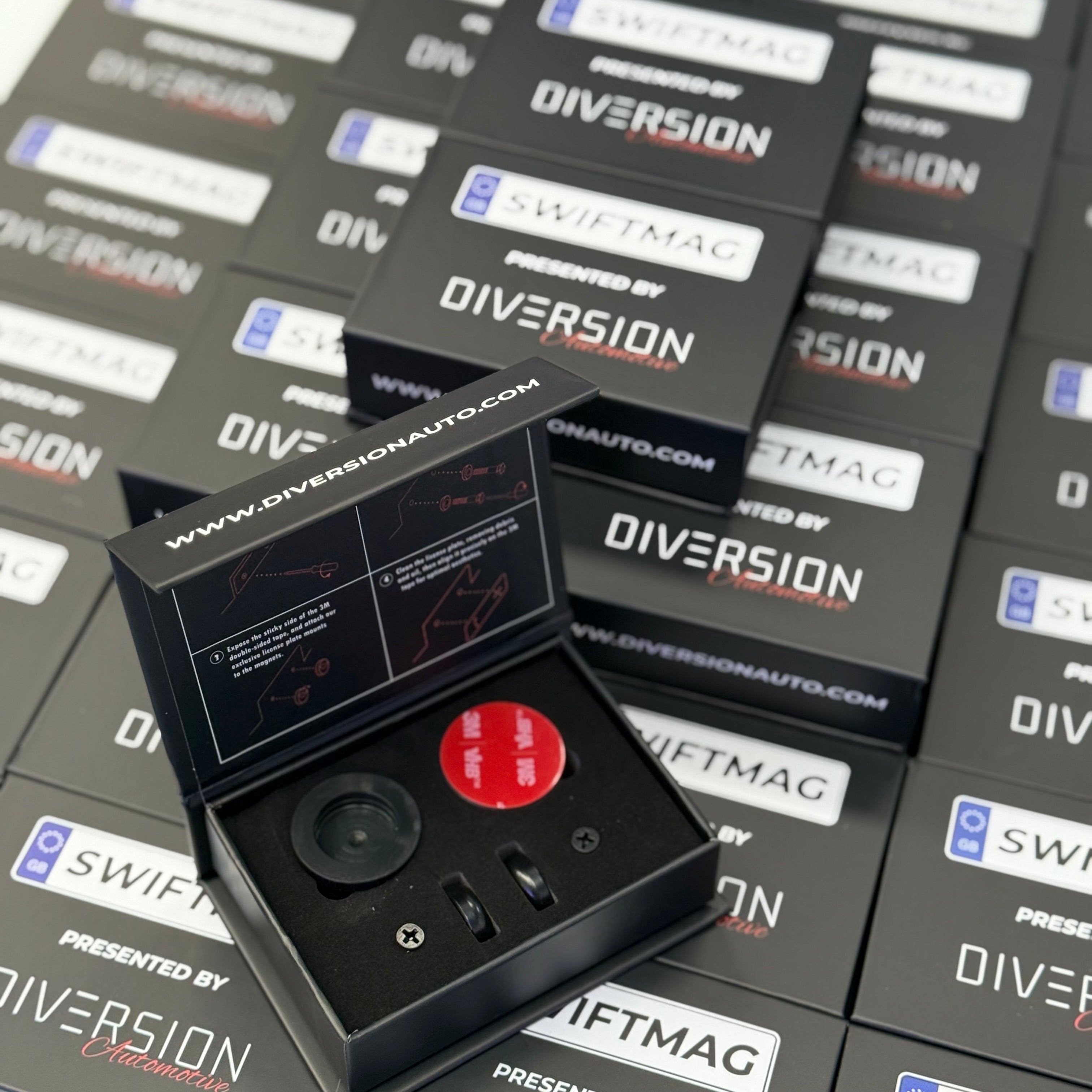 Black electronic device with a red button on top of 'Diversion' branded boxes.